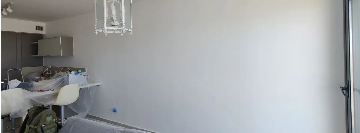 קיר לבן לאחר הכנה וצביעה, לצד רהיטים מכוסים